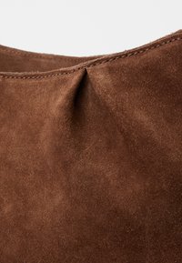 Brown suede bag with a soft texture. Features a gathered seam at the top and stitched edges for added detail.