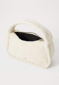 Borsa bianca dal tessuto soffice, con chiusura a zip e manico arrotondato. L'interno è nero, in contrasto con il design esterno.