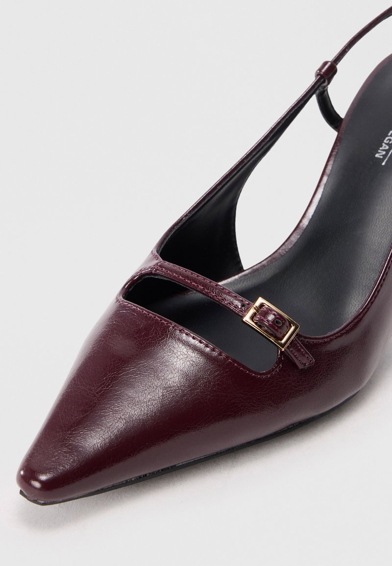 Chaussure slingback bordeaux avec un bout pointu, texture en cuir brillant, et une fine lanière avec un petit accent de boucle en or.