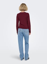 Haut à manches longues bordeaux avec un motif à pois subtil, associé à un jean évasé bleu clair. Le tissu semble doux et extensible.