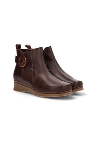 Botas de tobillo de cuero marrón con textura suave, puntera redondeada y tacón de goma bajo. Incluyen un corte lateral con un acento circular.
