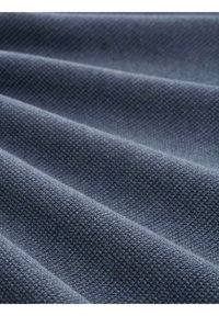 Tissu bleu marine texturé avec un motif tissé, présentant des plis et des drapés, mettant en valeur une texture douce et riche ainsi qu'une couleur profonde.