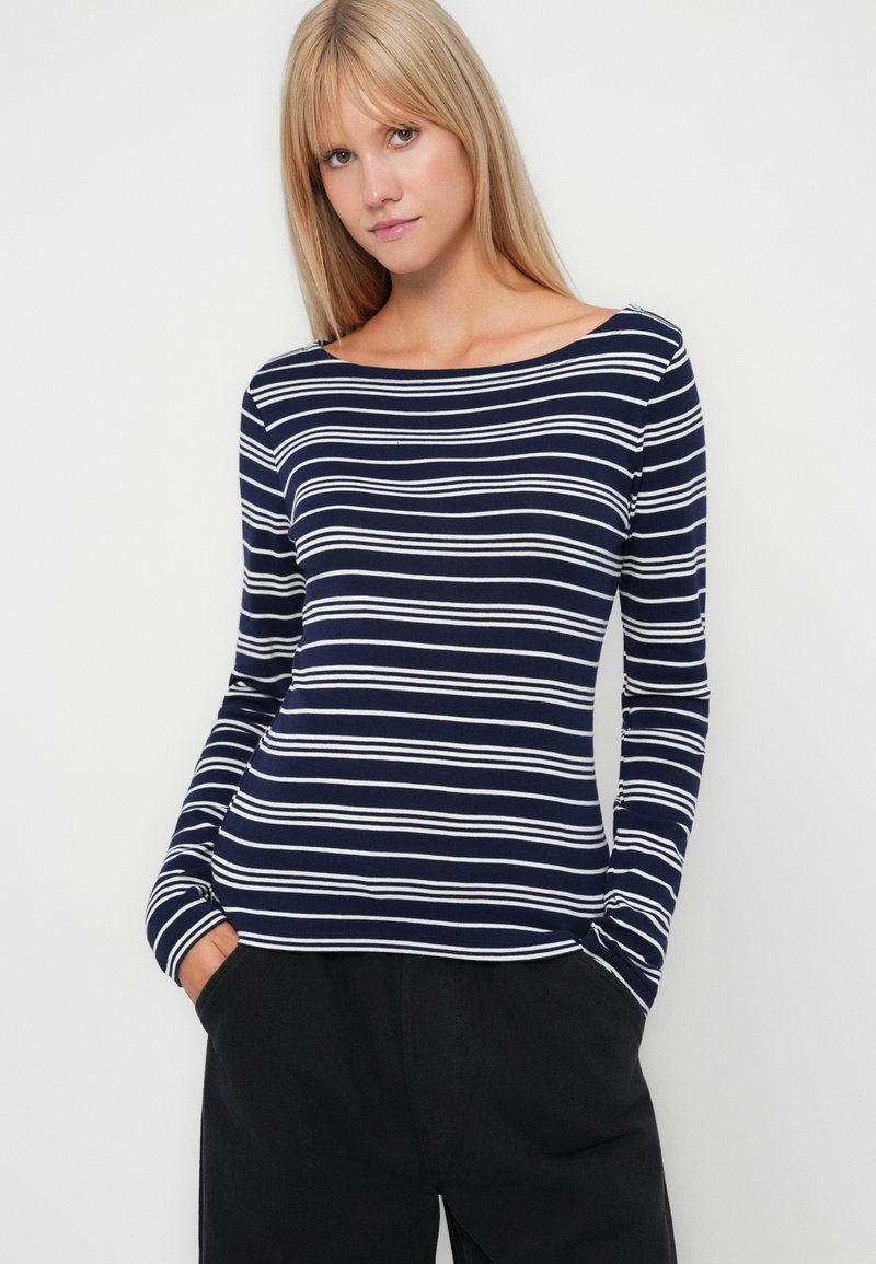 Marineblaues Langarmoberteil mit weißen horizontalen Streifen, Bootsausschnitt und elastischem Stoff. Hat eine entspannte Passform und gekrempelte Ärmel.