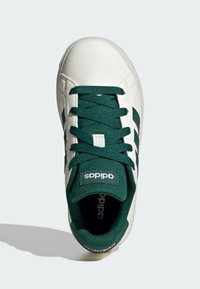 White sneaker with green accents, featuring a smooth leather upper, round toe, flat green laces, and three green stripes on the side.