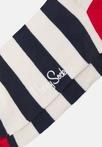 Juostuotos kojinės tamsiai mėlynos ir grietinėlės spalvos su raudonu akcentu. Medvilnės mišinio audinys, su balta logo "HappySock®".