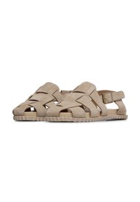 Sandalias de ante beige con punta abierta, correas entrelazadas, hebilla ajustable en el tobillo y suela de goma texturizada. Perfil plano para mayor comodidad.