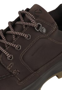 Braunes wasserdichtes Schuhwerk mit strukturiertem Leder-Obermaterial, kontrastierenden braunen Schnürsenkeln, sechseckigen Ösen und beiger Gummisohle mit Profilmuster.