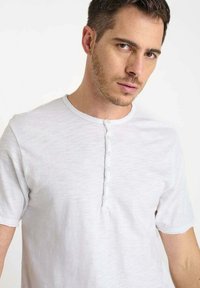 Korte mouwen, witte henley-shirt gemaakt van een dunne, zachte stof met een knopenlijst en een geribde kraag met een lichte textuur.
