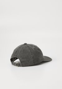Căciulă din denim gri, cu o coroană rotundă și o margine curbată, dotată cu accesorii metalice ajustabile și o textură moale. Vedere din spate.