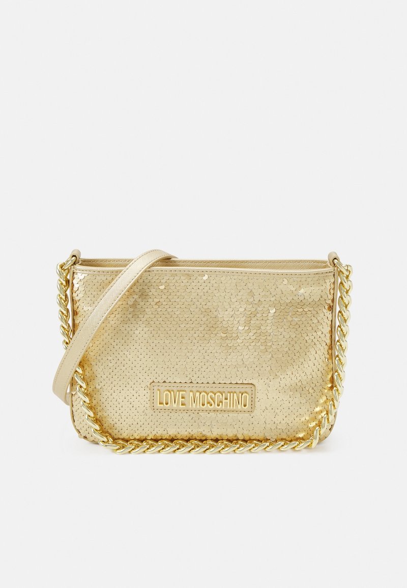 Gold sequined crossbody bag with a cream shoulder strap. Features a chain accent and a rectangular logo patch embossed on the front.