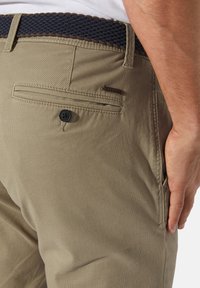 Beige cotton trousers with a textured finish, featuring a side pocket, button closure, and a dark braided belt.