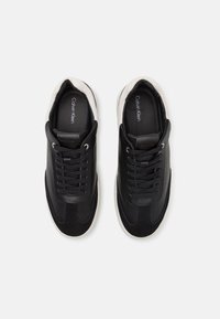 Sorte lær sneakers med suede-detaljer, snørebånd-design og hvite gummisåler. Har en glatt tekstur og subtil merking.