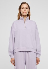 Helllila Zip-Hals Sweatshirt mit langen Ärmeln, lockerer Passform, gerippten Bündchen und Saum. Weicher Stoff mit minimalistischem Design und ohne Muster.