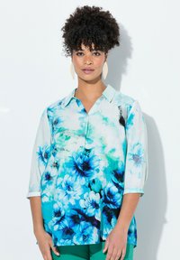 Blusa floreale in tonalità di blu e bianco, dotata di colletto e maniche a tre quarti. Tessuto leggero con una consistenza morbida.