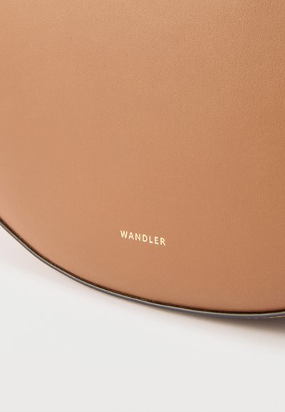 Καμπύλη επιφάνεια δέρματος ταμπά με ανάγλυφο χρυσό λογότυπο "WANDLER" κοντά στην άκρη, τοποθετημένη σε λευκό φόντο.