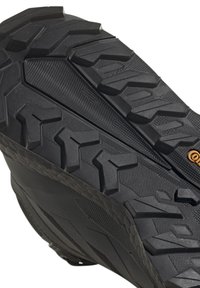 Schwarze Wanderstiefelsohle mit strukturiertem Gummi, tiefen Profilen und komplexen Mustern für verbesserten Halt und Traktion.