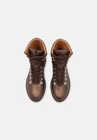 Stivali da trekking in pelle marrone con occhielli metallici, lacci marroni e una fodera arancione a contrasto, caratterizzati da un design robusto e una texture liscia.