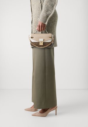 Beige patterned handbag with gold hardware, chain strap, and white accents. Worn alongside olive green wide-leg trousers and beige heels.