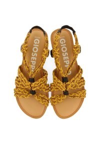 Sandalias trenzadas amarillas con acentos oscuros, que cuentan con una suela plana y múltiples correas entrelazadas. Plantilla suave y texturizada con la marca visible.