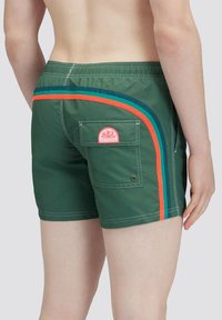 Groene zwemshorts met een achterzak, voorzien van blauwe, oranje en teal strepen langs de zijkanten, gemaakt van lichtgewicht materiaal.