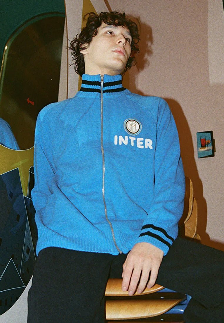 Blauwe ritstrui met zwarte strepen bij de kraag en boorden. Bevat een rond logo met de tekst "INTER" in het wit op de borst.