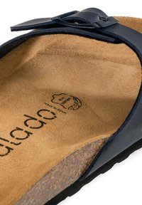 Marineblaue Sandale mit einem Korkfußbett, einem Obermaterial aus Leder mit einer Schnallenakzentuierung und einer weichen, strukturierten Fütterung. Flacher Absatz mit leichter Fußgewölbeunterstützung.