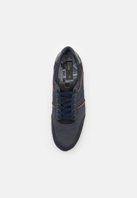 Marine sneaker met een geperforeerde bovenkant, bruine accentstreep en donkerblauwe veters. Interieur met een patroonontwerp en branding.