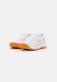 White athletic shoes with breathable mesh upper, contrasting orange rubber sole, and subtle gray branding accents on the sides.