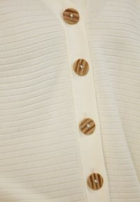 Crème-kleurige geribde cardigan met vijf houten knopen, met horizontale textuur en een V-hals ontwerp. Zachte gebreide stof.