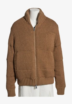 Pull en maille épaisse marron avec fermeture éclair, col montant et poignets et ourlet côtelés, présenté sur un mannequin portant une jupe blanche.