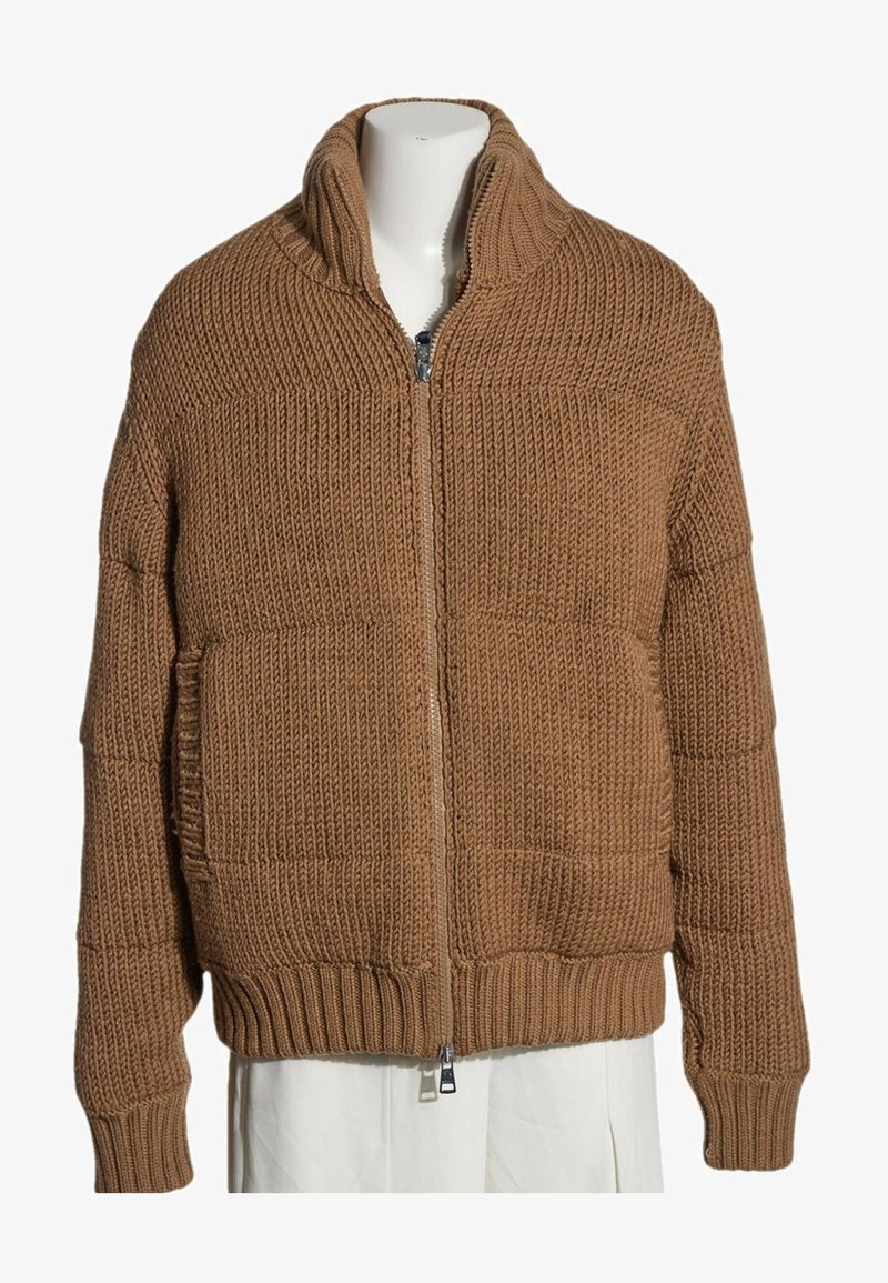 Pull en maille épaisse marron avec fermeture éclair, col montant et poignets et ourlet côtelés, présenté sur un mannequin portant une jupe blanche.