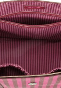 Zippered bag interior in deep pink with dark pink vertical stripes. Features a brand label and a gathered pocket for additional storage.