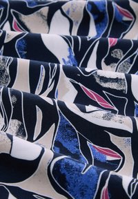 Stof met een donkerblauwe achtergrond, versierd met gestileerde, abstracte bladvormen in beige, blauw en subtiele rode accenten, met een textuuri uiterlijk.