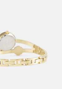 Goldfarbene Armbanduhr mit silbernem Zifferblatt, ausgestattet mit einem verlinkten Armbanddesign und gravierten Logoakzenten. Minimalistisches rundes Gehäuse mit glatter Oberfläche.
