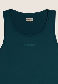 Camiseta sin mangas de color verde azulado oscuro hecha de tela suave, con un escote redondo y el nombre de la marca "FREDDY" impreso en un tono más oscuro.