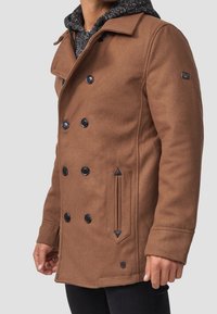Brun uldblande peacoat med en dobbeltrækket design, sorte knapper og en tekstureret grå hætteforing.