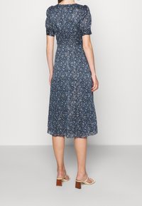 Vestido midi azul con flores, con un corsé ajustado y mangas abullonadas, que presenta una parte trasera fruncida y una falda fluida que termina por debajo de la pantorrilla.