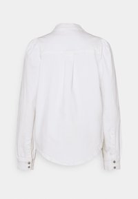 Camicia bianca a maniche lunghe con colletto classico, polsini abbottonati e dettaglio di piega sul retro. Realizzata in un tessuto leggero con una texture liscia.