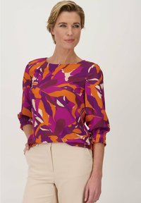 Kleurrijke blouse met een bloemmotief in paars, oranje en crème, met een ronde halslijn en driekwart gerimpelde mouwen.