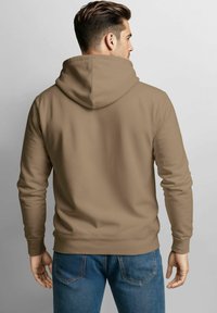 Brown hoodie with a drawstring, smooth texture, and a kangaroo pocket, paired with blue jeans featuring a classic pocket design.