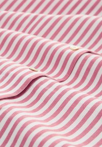 Tessuto a righe in rosa e bianco, con una texture morbida e un dettaglio a bottone, caratterizzato da linee orizzontali di larghezza uniforme.