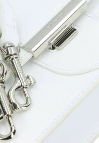 Borsa a mano in pelle bianca con hardware argentato, chiusura in metallo e tracolla removibile con ganci a rotazione. Dettagli cuciti lungo i bordi.