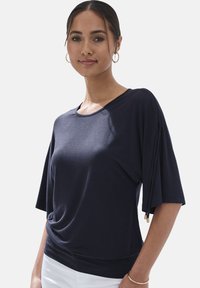 Top de manga corta azul marino con un ajuste relajado, que presenta lazos laterales y un escote redondeado. Fabricado en una tela suave y ligera.