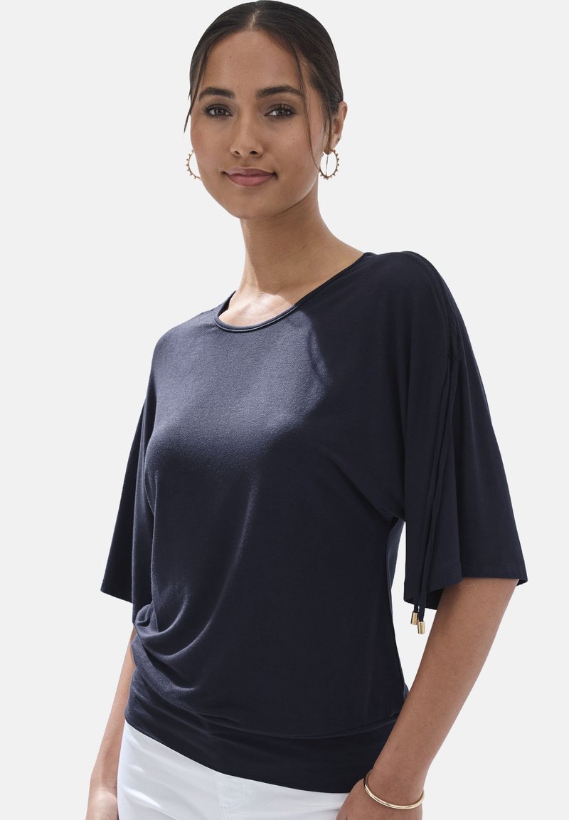 Top de manga corta azul marino con un ajuste relajado, que presenta lazos laterales y un escote redondeado. Fabricado en una tela suave y ligera.