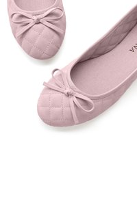 Helles rosa, gesteppte Ballerinas mit runder Zehenpartie, die ein kleines Schleifendetail an der Vorderseite und ein glattes Stofffutter innen haben.