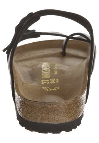 Sandalia de tiras negra con plantilla de corcho texturizado y suela de goma. Presenta una tira curvada con acentos decorativos y la talla impresa en el interior.