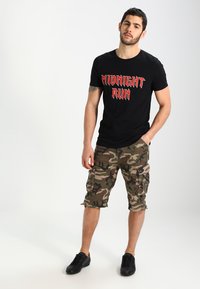 Schwarzes Baumwoll-T-Shirt mit rotem „MIDNIGHT RUN“-Grafik; camouflage Cargo-Shorts; schwarze Sneakers; lässiger Schnitt.