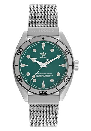 Montre en acier inoxydable avec un cadran teal, des index argentés et un bracelet en maille. Elle dispose d'une lunette rotative et d'un logo adidas sur le cadran.