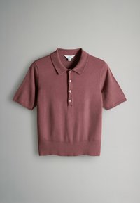 Polo majica kratkih rukava u prigušenoj mauve boji, izrađena od mekanog pletiva. Ima klasičan ovratnik, placket sa četiri dugmeta i uski rub.