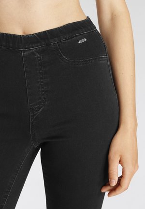 Zwarte denim jeans met een gladde textuur, elastische tailleband en voorzak. Bevat subtiele branding op de tailleband.